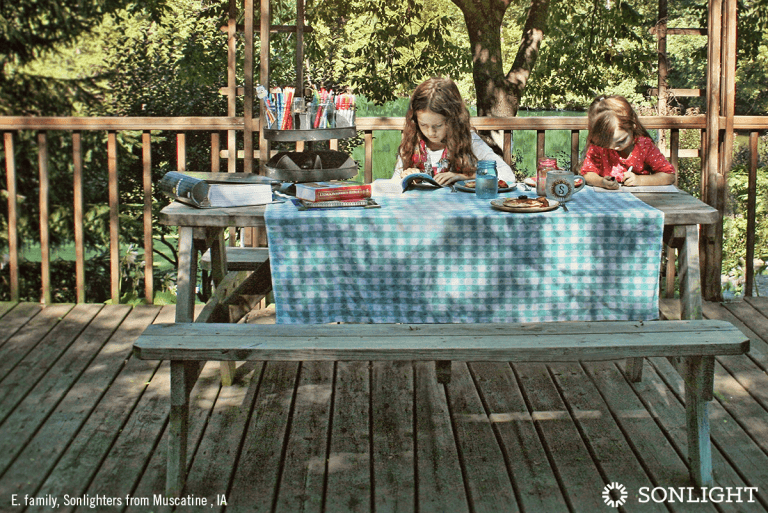 two sisters read at an outdoor picnic table