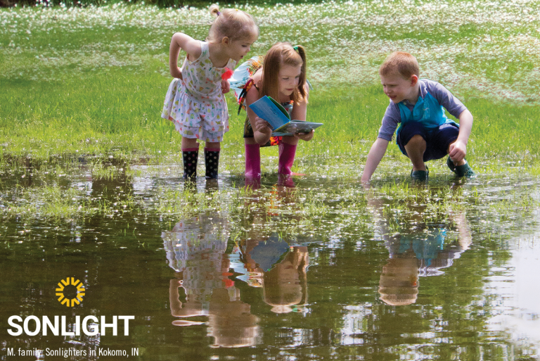 three children explore a pond