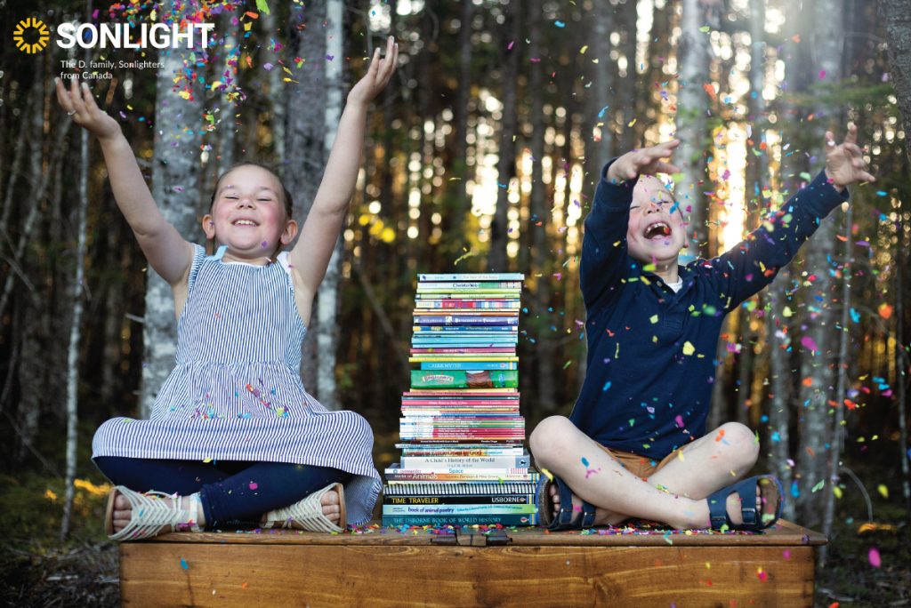 two children sit on either side of a stack of books