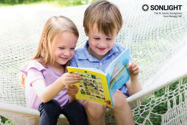 brother and sister look at a book while sitting on a hammock