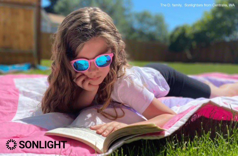 Sonlighter reading outside on a sunny day with sunglasses on. 

The D. Family, Sonlighters in WA
